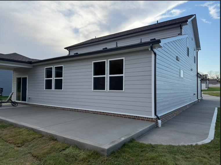 Custom concrete patio with deck stairs viewed from backyard in Clarksville, TN