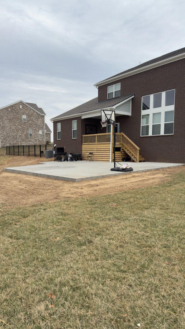Custom concrete patio with deck stairs viewed from backyard in Clarksville, TN